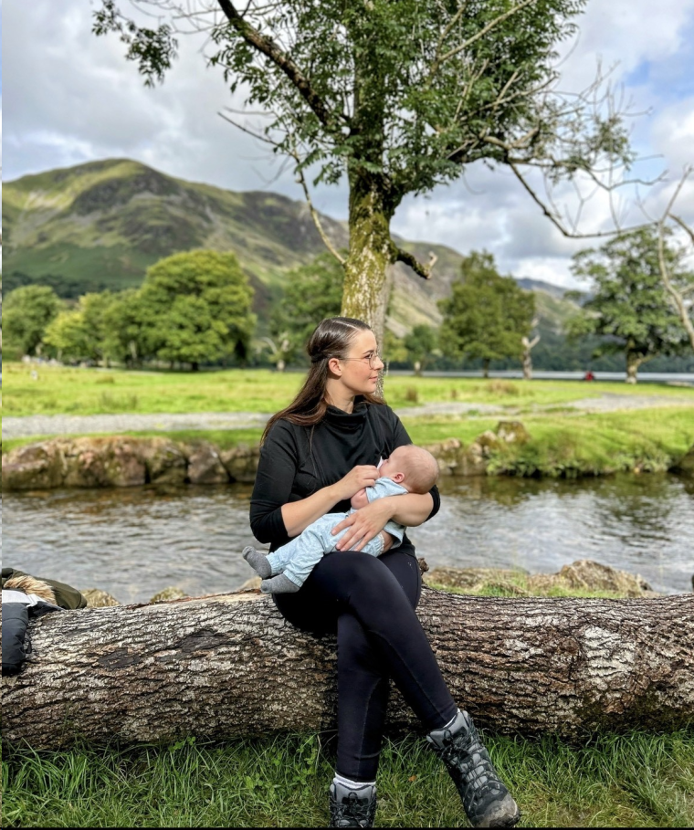 Natalie sitting on a log breastfeeding in the Lake District.